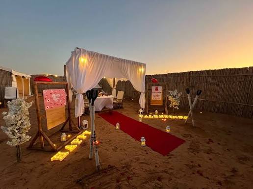 A long lantern-lit table set for a team dinner in the desert