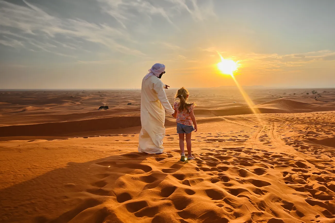 Guests watching the sunset from a red dune